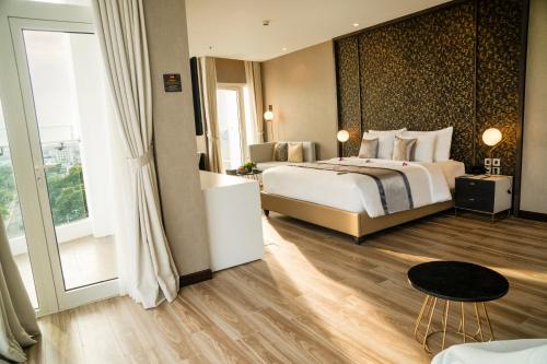 een hotelkamer met een bed en een groot raam bij Diamond Stars Ben Tre Hotel in Ben Tre