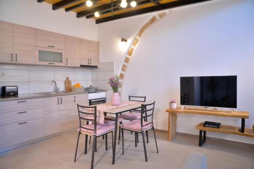 een keuken met een tafel en stoelen en een televisie bij VAMA APARTMENT in Plataniás