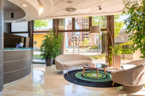 a lobby with chairs and a coffee table in a building at Savhotel Aemilia Bologna in Bologna