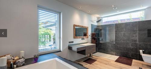 a bathroom with a tub and a sink and a window at Alpin Chalet Arte in Söll