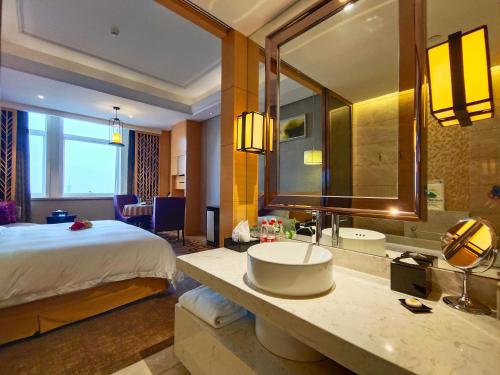 a hotel room with a bed and a bathroom with a sink at Yangzhong Firth Jinling Grand Hotel in Yangzhong