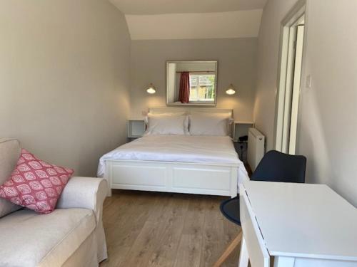 ein kleines Schlafzimmer mit einem Bett und einer Couch in der Unterkunft Far Hill Studio in Wyck Rissington