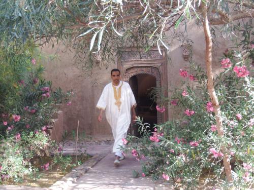 a man walking through a garden with pink flowers at Dar Paru in Mhamid