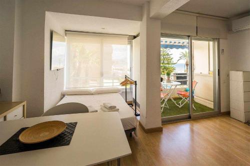 1 dormitorio con cama, mesa y balcón en Voramar Estudio 3Pax primera linea Playa San Juan, en El Campello