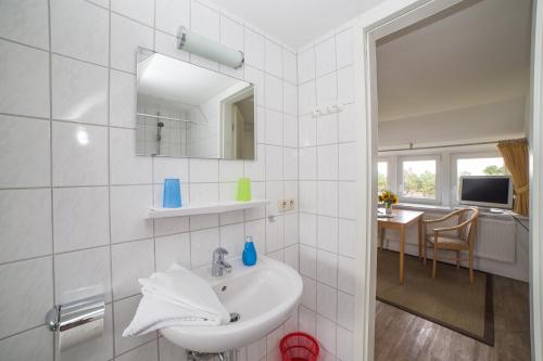 ein weißes Badezimmer mit einem Waschbecken und einem Spiegel in der Unterkunft Haus Bräätlun Ferienwohnung Bräätlun 2 in Norddorf