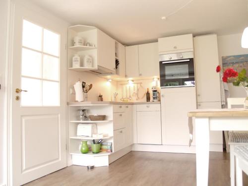 Una cocina blanca con gabinetes blancos y una ventana. en Haus Anneliese Bungalow Düne, en Norddorf