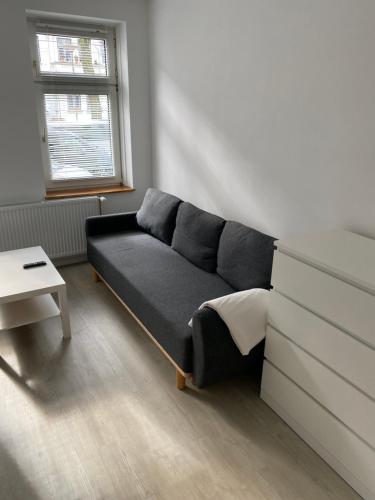 ein schwarzes Sofa in einem Zimmer mit Fenster in der Unterkunft Zentrale und schöne Ferienwohnung in Lübeck