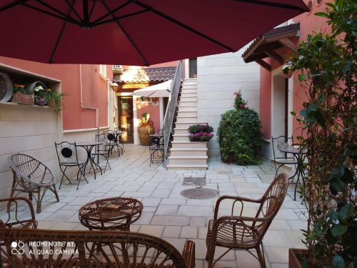 une terrasse avec des chaises, des tables et un parasol dans l'établissement B&B Corte Dei Figuli, à San Pietro in Lama