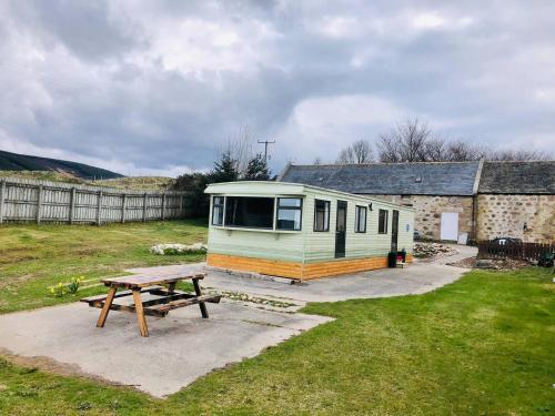 a tiny house with a picnic table in a yard at Lettoch Farm Holiday Home in Dufftown