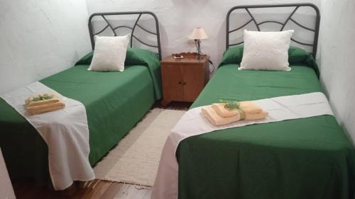 2 camas en una habitación con sábanas verdes y toallas en Casa Osciris, en El Cercado