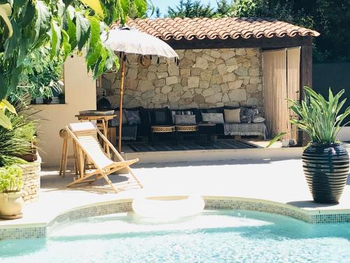 una piscina con una silla y una sombrilla junto a una casa en VILLA MATHIS, en Mouans-Sartoux