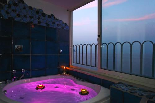 bagno con vasca rosa e finestra di Hotel La Ninfa ad Amalfi