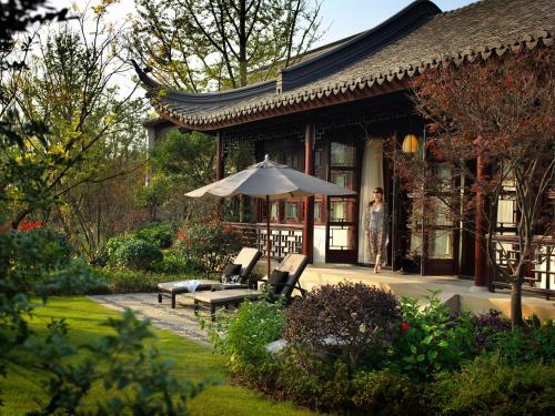 uma mulher do lado de fora de uma casa com um guarda-chuva em Four Seasons Hotel Hangzhou at West Lake em Hangzhou