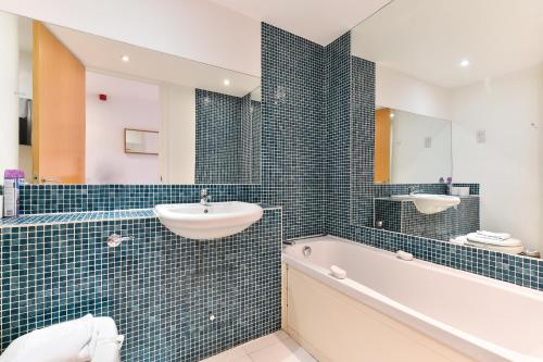 a bathroom with a tub and a sink and a bath tubermottermott at Liverpool Street City Living in London