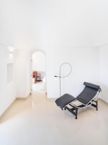 a black chair in a white room with a mirror at Trulleria Alchimia in Selva di Fasano