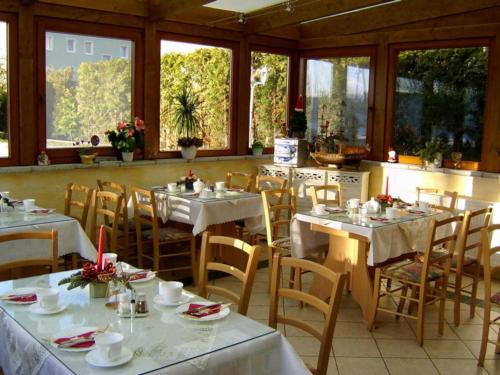 黑靈斯多夫的住宿－Pension Mittag，餐厅设有白色的桌椅和窗户。