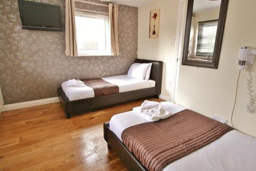 a small room with two beds and a tv at Central Studios Gloucester Road by RoomsBooked - Free Parking in Cheltenham