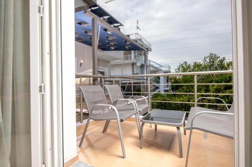 a balcony with chairs and tables on a balcony at StayInn Luxury Apartments in Nea Kalikratia