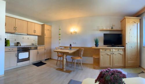 une cuisine avec des placards en bois et une table avec une télévision dans l'établissement Birkenhof, à Leutasch