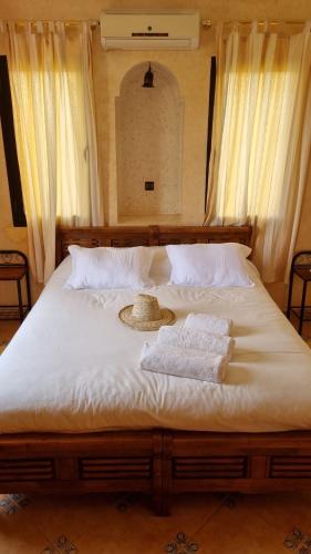 a bed with a hat and two towels on it at Le Beau Site Ourika in Aghmat