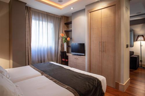 um quarto com uma grande cama branca e uma televisão em Washington Parquesol Suites & Hotel em Valladolid