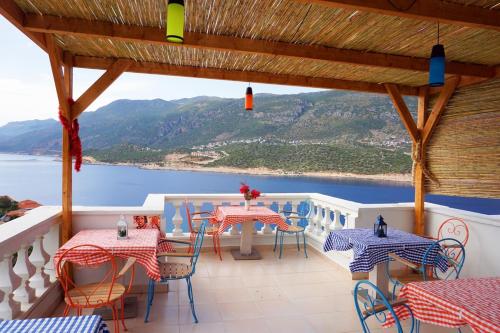 a balcony with tables and chairs and a view of the ocean at Düşler Evim Butik Otel in Kaş