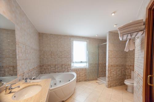a bathroom with a tub and a sink and a toilet at Hotel Andia in Orcoyen