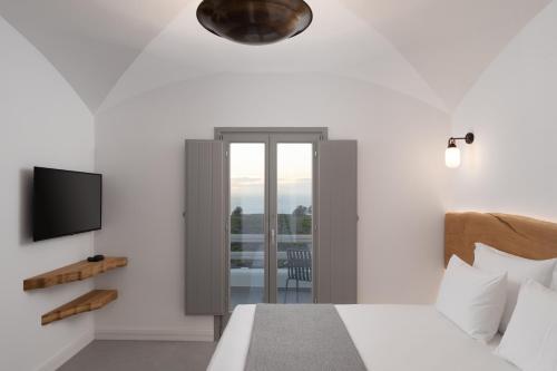 a bedroom with a bed and a tv and a balcony at La Ponta Villas & Suites in Akrotiri