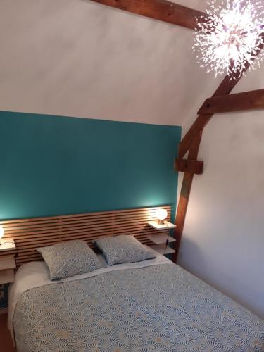 a bedroom with a blue headboard and a bed with two pillows at La Fée des Eaux in Vernaison