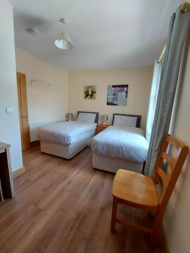 two beds and a chair in a room with wooden floors at Red Door Townhouse in Galway