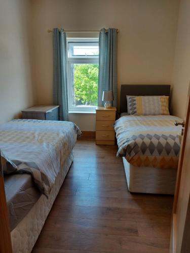 two beds in a room with a window at Red Door Townhouse in Galway