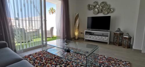 a living room with a television and a glass table at Villa Hortensia in Adeje