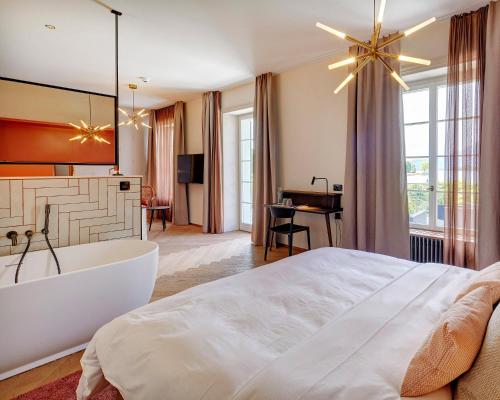 a bedroom with a large white bed and a tub at Hotel Restaurant Seehof in Küssnacht