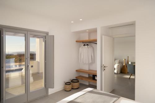 a bedroom with white walls and a sliding glass door at La Ponta Villas & Suites in Akrotiri