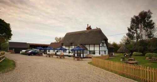 a building with a thatched roof with picnic tables at The Bottle & Glass Inn in Harpsden