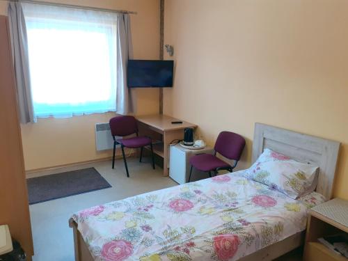 1 Schlafzimmer mit einem Bett, 2 Stühlen und einem Schreibtisch in der Unterkunft Kambarių nuoma - Neveronys SAURIDA in Neveronys