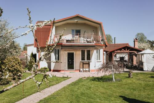 uma grande casa branca com um alpendre e um quintal em Guest House Lorem em Daugavpils