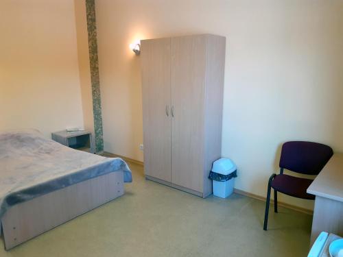 um quarto com uma cama, um armário e uma cadeira em Kambarių nuoma - Neveronys SAURIDA em Neveronys