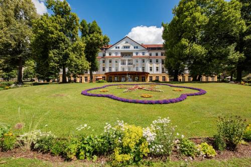 a large building with a clock in the middle of a park at Kulturhotel Kaiserhof in Bad Liebenstein