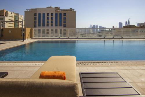 a couch sitting next to a swimming pool on a building at TIME Asma Hotel in Dubai
