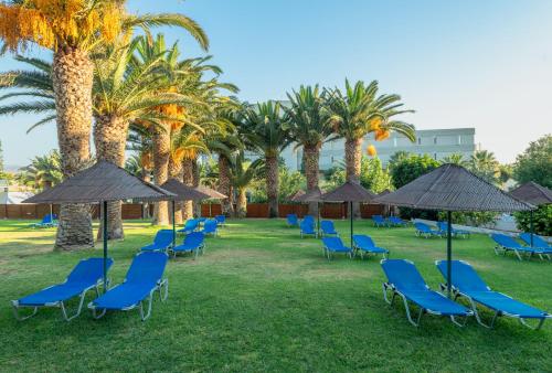 a row of chairs and umbrellas and palm trees at CHC Marilena Hotel in Amoudara Herakliou