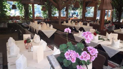 une salle à manger avec des tables blanches et des fleurs roses dans l'établissement Gasthof Erzherzog Rainer - Zimmer und Ferienwohnung, à Kössen