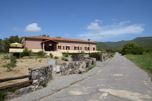 a house with a stone wall next to a road at Marrubiu Resort Note di Stelle in Marrùbiu