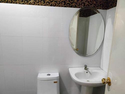 een badkamer met een wastafel, een spiegel en een toilet bij RedDoorz @ Villa E Mansion in Vigan