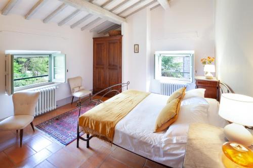 ein Schlafzimmer mit einem Bett und zwei Fenstern in der Unterkunft Locanda Quattro Vesta in San Casciano dei Bagni