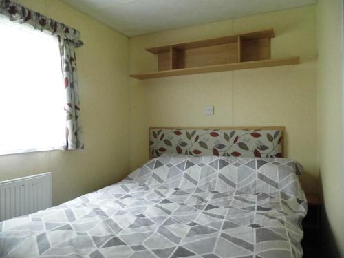a bedroom with a bed and a window at Oakdene -3 Bedroom Caravan in Weeley