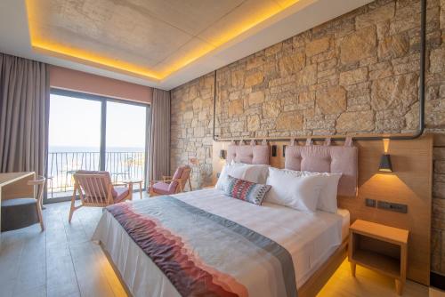a bedroom with a large bed and a stone wall at Cape Krio Boutique Hotel & SPA - Over 12 years old Adult Only in Datca