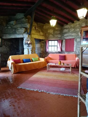 a living room with two couches and a table at Salto do Lobo - Montain houses with private river in Penhas da Saúde