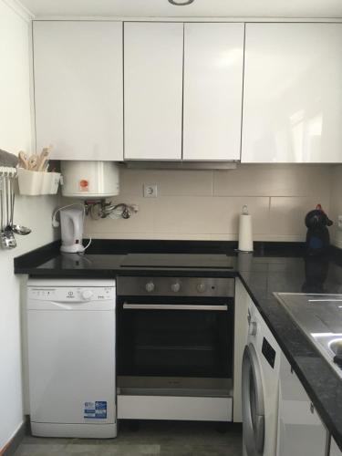 a kitchen with white cabinets and a dishwasher at Capuchos Terrasse in Caparica