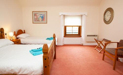 a bedroom with two beds and a clock on the wall at Balintore Inn in Balintore
